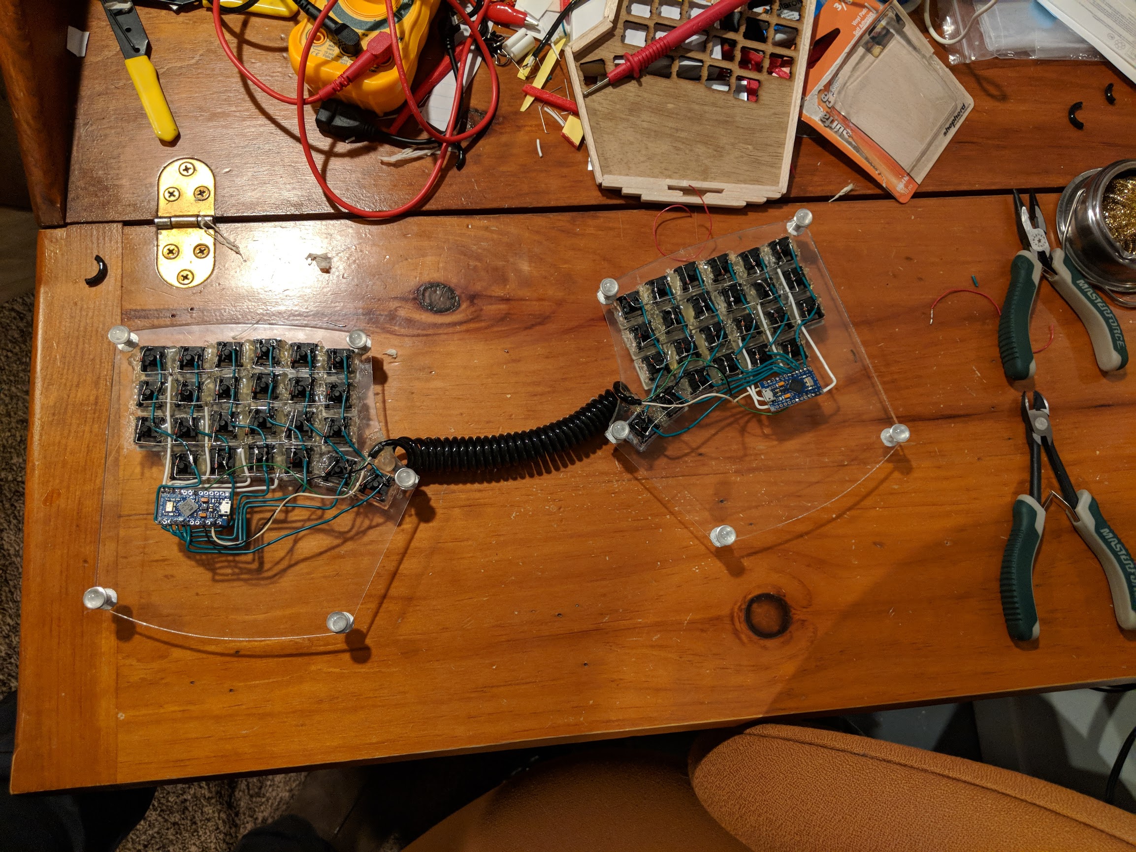 Bottom of transparent keyboard plates with micro controllers installed and a wire connecting them slit